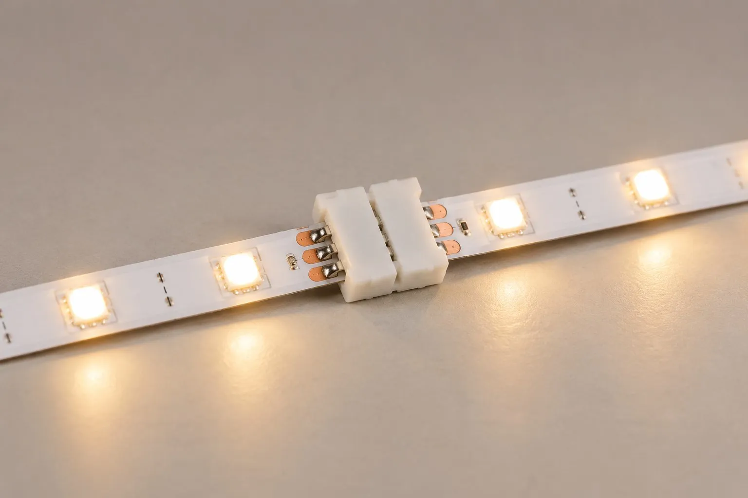 A solderless clip-on gapless connector clamped onto the copper pads of a cut LED strip, joining two segments without a soldering iron