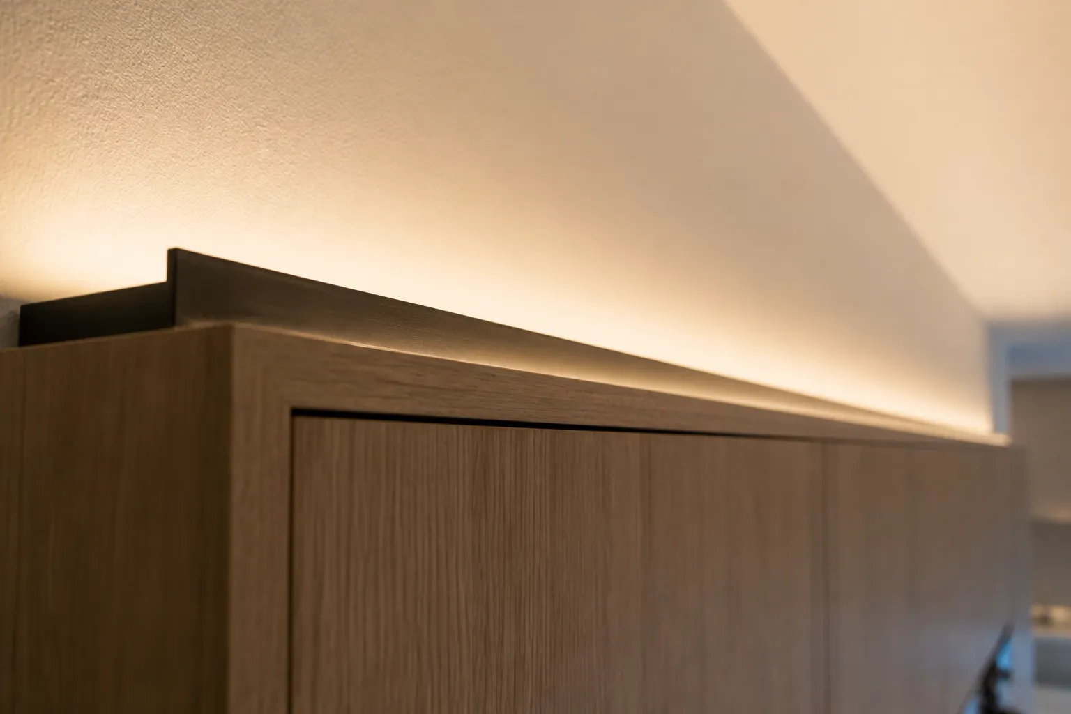 LED strip in an aluminum channel on top of kitchen wall cabinets, washing the ceiling with an even band of warm light and no visible diodes