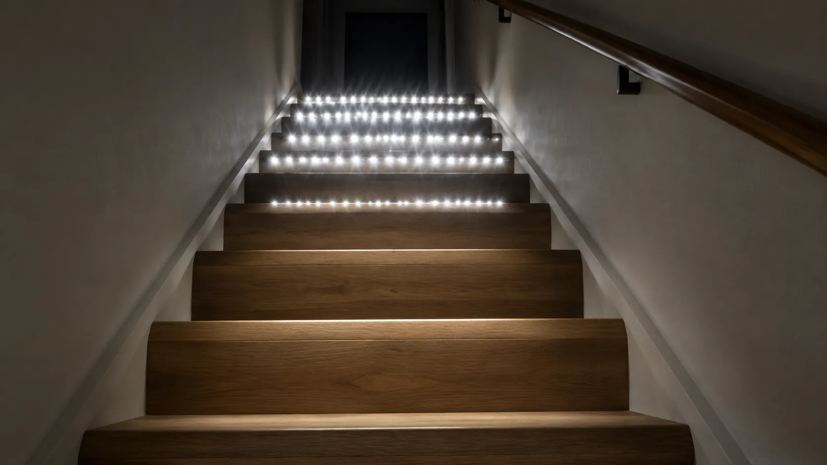 Looking up a staircase from the bottom step at bare LED tape under the upper nosings, rows of harsh bright dots