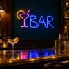 Custom LED neon bar sign with a pink cocktail glass, yellow lemon slice and blue BAR lettering above a bar counter