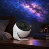 White globe-style galaxy star projector on a bedside table casting a purple galaxy and stars on the ceiling
