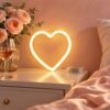Warm white heart shaped neon light on a bedside table, wired to a clear battery box