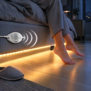 Under bed lights: a motion-sensor LED strip lighting the floor beside a bed frame as bare feet step down at night