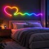 RGBIC neon rope light shaped into a heart and a wave above a bed, with a phone showing the colour app