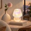 Speckled iridescent glass mushroom table lamp glowing warm on a stack of books