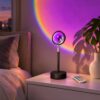 Stem sunset projection lamp with remote casting a purple glow with a rainbow edge on a bedroom wall